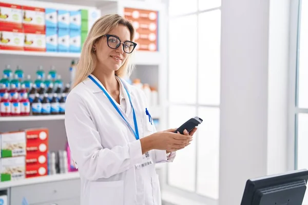 Young Blonde Woman Pharmacist Using Data Phone Working Pharmacy — ストック写真