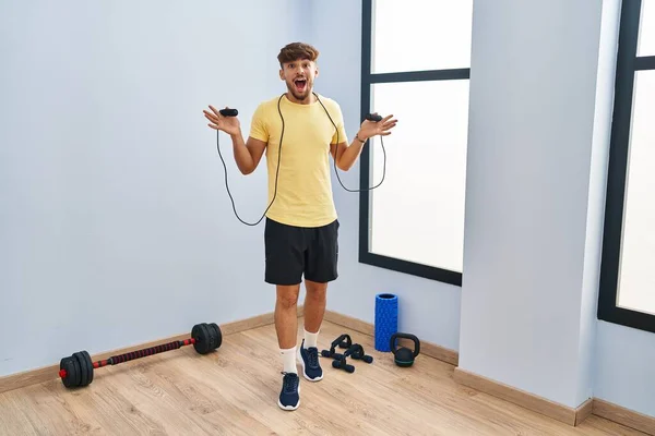 Arab man with beard training with jump rope celebrating crazy and amazed for success with open eyes screaming excited.
