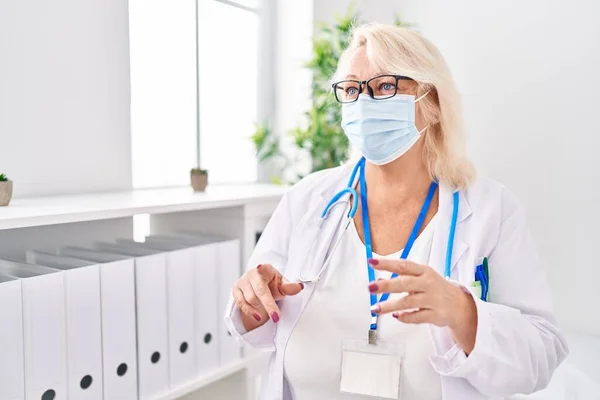 Klinikte Orta Yaşlı Sarışın Kadın Doktor Üniforması Giyiyor Tıbbi Maske — Stok fotoğraf