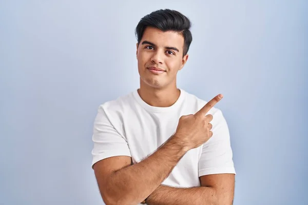 拉美裔男子站在蓝色的背景上 手指头指向广告的侧面 严肃而沉着 — 图库照片