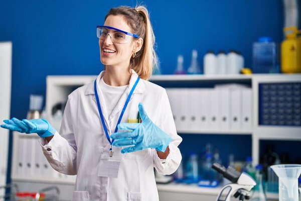 Young woman scientist smiling confident speaking at laboratory