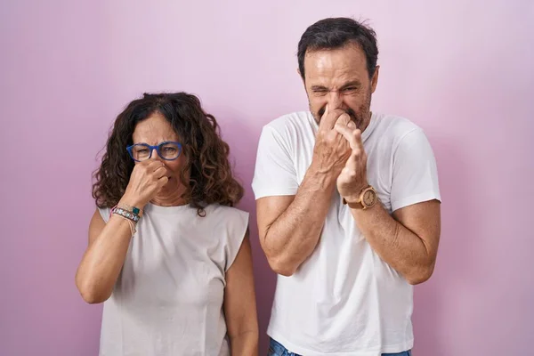 Casal Hispânico Meia Idade Juntos Sobre Fundo Rosa Cheirando Algo — Fotografia de Stock