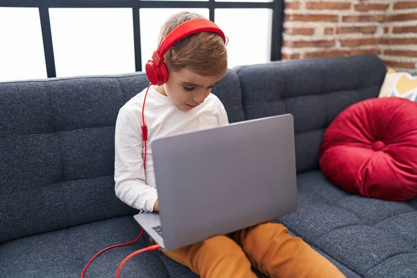 Adorable Hispanic Boy Using Laptop Headphones Sitting Sofa Home — Foto Stock