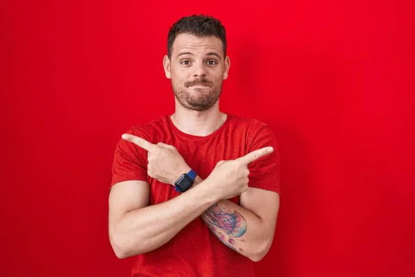 Young Hispanic Man Standing Red Background Pointing Both Sides Fingers — Stockfoto