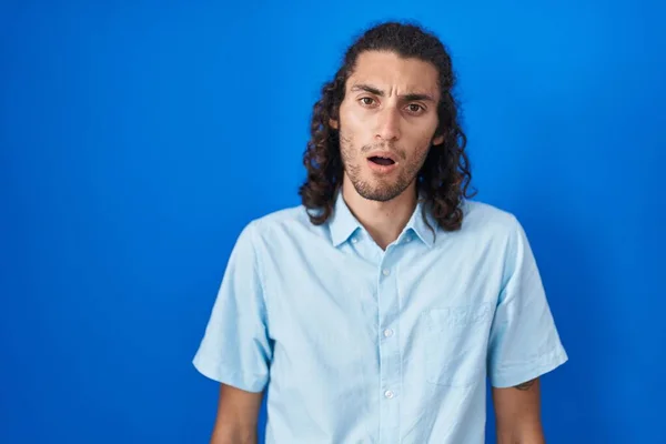 Ung Latinamerikansk Man Står Över Blå Bakgrund Chock Ansikte Ser — Stockfoto