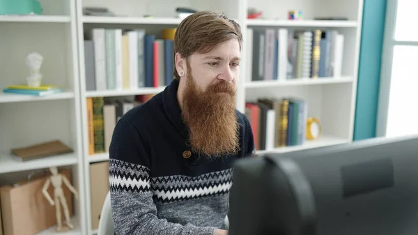 図書館大学でコンピュータを勉強している若い赤毛の学生 — ストック写真
