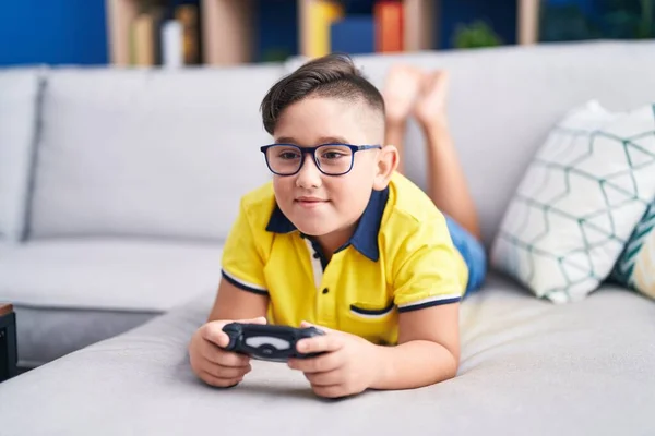 Joven Niño Hispano Jugando Videojuego Sosteniendo Controlador Sofá Guiñando Ojo —  Fotos de Stock