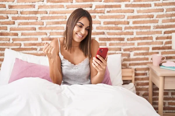 Молода Іспаномовна Жінка Використовуючи Смартфон Сидячи Ліжку Вдома Кричить Гордо — стокове фото
