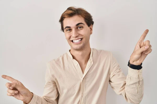 年轻男子站在孤独的背景上 带着自信的微笑 用手指指向不同的方向 复制广告空间 — 图库照片