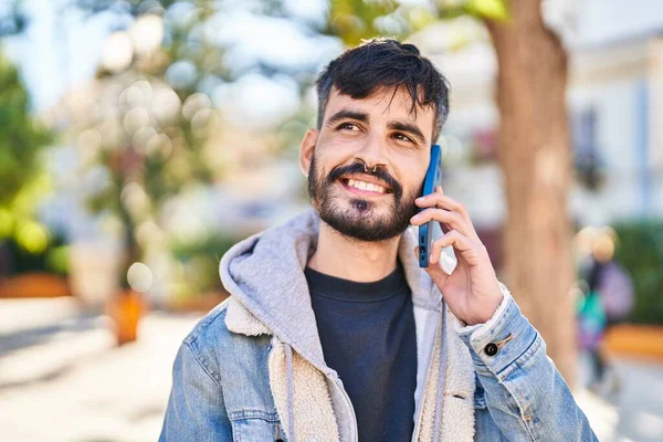 Genç İspanyol adam gülümsüyor. Parktaki akıllı telefondan konuşuyor.