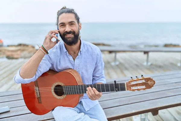 Young Hispanic Man Musician Holding Classical Guitar Talking Smartphone Seaside — Fotografia de Stock