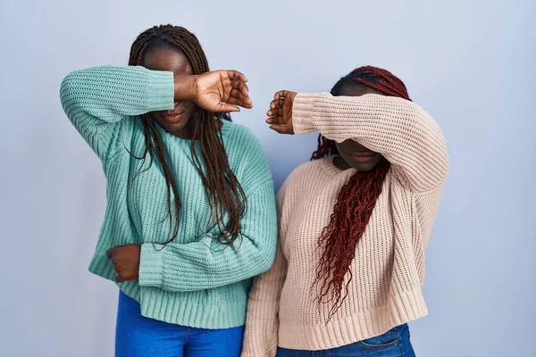 Две Африканки Стоящие Синем Фоне Закрывая Глаза Рукой Выглядят Серьезными — стоковое фото