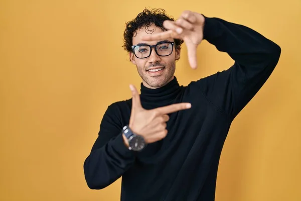Hispanic Man Standing Yellow Background Smiling Making Frame Hands Fingers — Zdjęcie stockowe