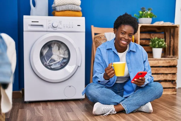 Africano Americano Mulher Usando Smartphone Beber Café Espera Máquina Lavar — Fotografia de Stock