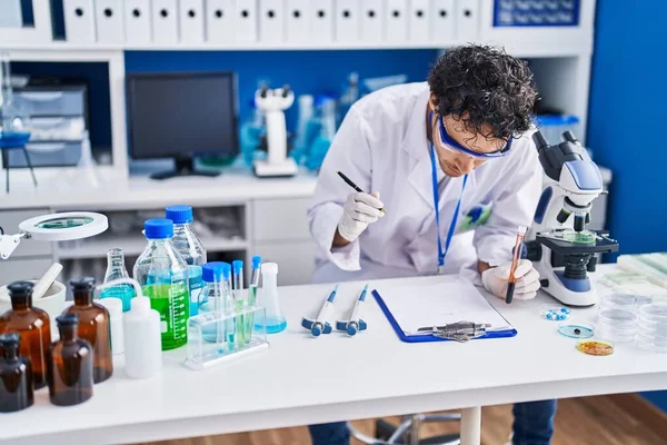 Young Hispanic Man Scientist Writing Document Holding Blood Test Tube — Zdjęcie stockowe