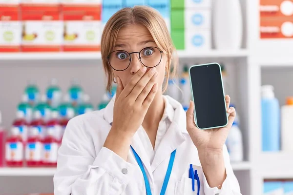 약국에서 일하는 코카서스 여성은 실수로 충격을 두려워하는 손으로 가리는 스마트폰 — 스톡 사진
