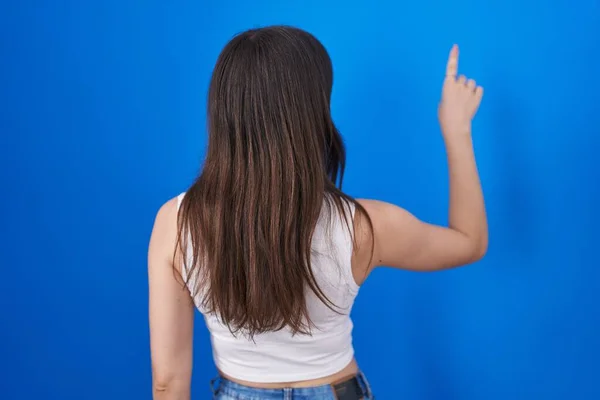 Jonge Blanke Vrouw Staande Blauwe Achtergrond Poseren Achteruit Wijzen Vooruit — Stockfoto