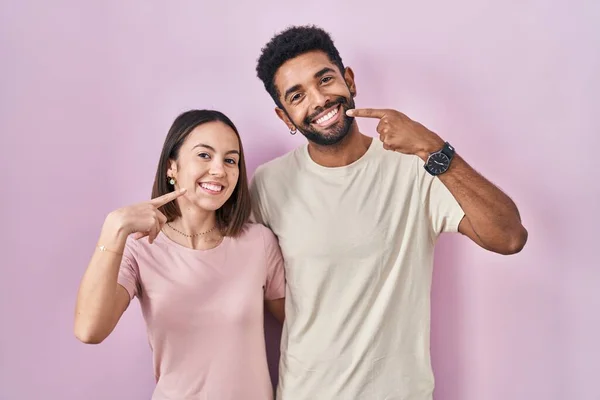 Junges Hispanisches Paar Zusammen Über Rosa Hintergrund Lächelnd Fröhlich Zeigend — Stockfoto