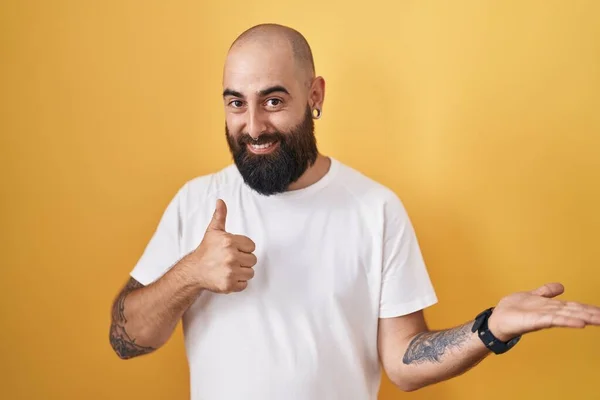 Mladý Hispánec Vousy Tetováním Stojící Nad Žlutým Pozadím Ukazující Dlaň — Stock fotografie