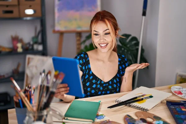 若い白人女性は幸せな笑顔で達成を祝うタブレットとビデオ通話を行い アートスタジオに座っていると勝者式とともに上げ手 — ストック写真