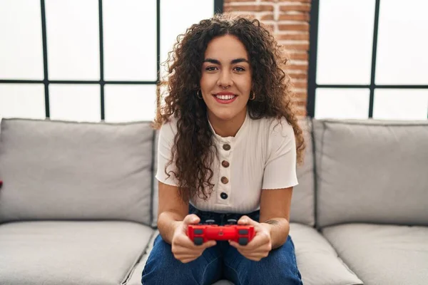 stock image Young beautiful hispanic woman playing video game sitting on sofa at home