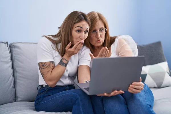 母と娘使用してノートパソコン上のソファに家に座って — ストック写真