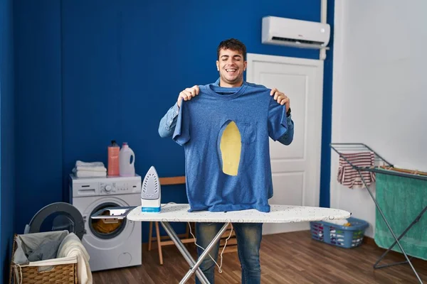 Jovem Hispânico Homem Engomar Segurando Queimado Camisa Ferro Lavanderia Sorrindo — Fotografia de Stock