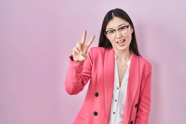 中国商界年轻女子戴着眼镜 微笑着看着摄像机 手指头在做胜利的标志 第二点 — 图库照片