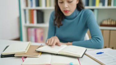 Genç, güzel İspanyol kadın üniversite sınıfında oturmuş kitap okuyor.