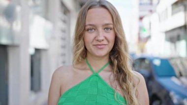 Genç sarışın kadın gülümsüyor. Elinde kredi kartı tutuyor.