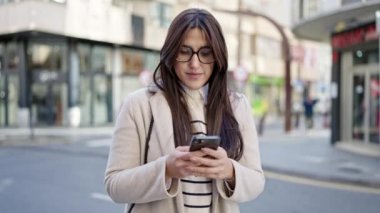 Genç ve güzel İspanyol kadın akıllı telefon kullanıyor. Sokakta ciddi bir ifadesi var.