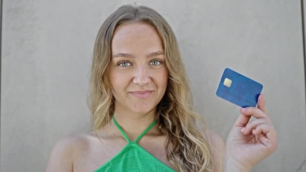 Młoda Blondynka Uśmiechnięta Pewnie Trzymając Kartę Kredytową Odizolowanym Białym Tle — Wideo stockowe