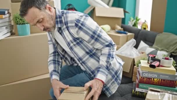 Hombre Mediana Edad Sentado Sofá Desembalaje Caja Cartón Nuevo Hogar — Vídeos de Stock