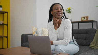 African american woman using laptop sitting on sofa at home