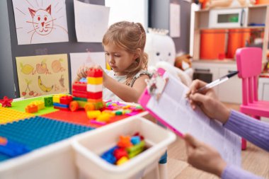 İnşaat bloklarıyla oynayan sevimli sarışın kız anaokulunda terapi görüyor.