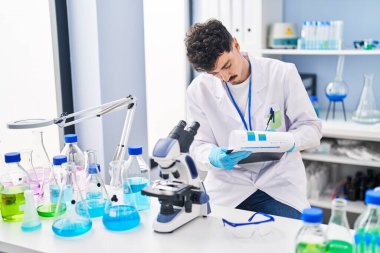 Young caucasian man scientist reading report working at laboratory