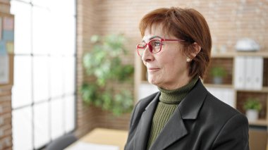 Ofisteki pencereden bakan yetişkin bir İspanyol iş kadını.