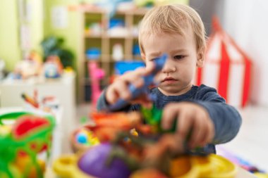 Sevimli sarışın çocuk kreşte oyun mutfağıyla oynuyor.