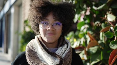 Sokakta kendinden emin gülümseyen Afrikalı Amerikalı genç bir kadın.