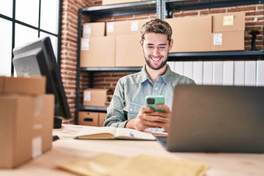 Young man ecommerce business worker using laptop and smartphone at office