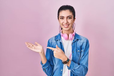 Pembe arka planda duran genç ve güzel bir kadın kameraya hayret ediyor ve gülümsüyor.. 