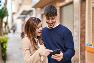 Mand and woman couple using smartphone standing together at street