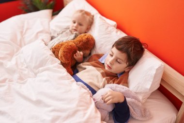 Sevimli erkek ve kız sarılıyor oyuncak ayıya. Yatak odasında uyuyor.