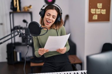 Genç, güzel, İspanyol bir müzisyen müzik stüdyosunda kendine güvenen bir şarkı söylüyor.