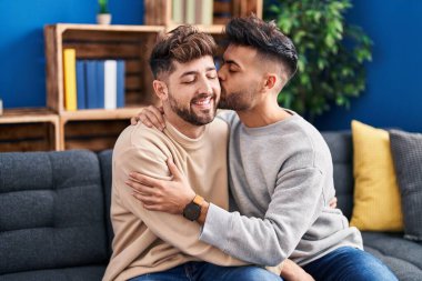 Young couple hugging each other sitting on sofa at home