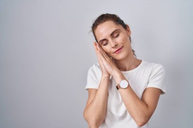 Güzel esmer kadın izole edilmiş arka planda ayakta uyur, yorgun düşler görür ve elleri ile birlikte poz verir, gözleri kapalı gülümserdi.. 