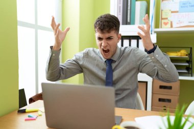 Young hispanic man business worker angry screaming at office