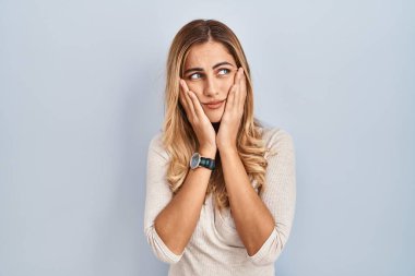 İzole edilmiş arka planda duran genç sarışın kadın yorgun eller, yüzü, depresyonu ve üzüntüyü örten, sorun yüzünden üzgün ve tedirgin 