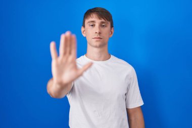 Mavi arka planda duran beyaz, sarışın bir adam avucunun içinde şarkı söylemeyi kesiyor. Yüzünde olumsuz ve ciddi bir jest olan uyarı ifadesi. 