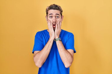 Sarı arka planda duran İspanyol sakallı adam korkmuş ve şok olmuş, şaşırmış ve şaşırmış bir yüz ifadesi var. 